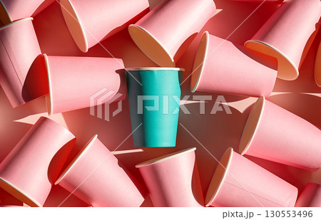 Teal paper cup stands out among many pink paper cups. Individuality and uniqueness concept Teal paper cup stands out among many pink paper cups. Individuality and uniqueness concept 130553496