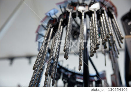 A whole bunch of various drill bits are hanging from a rack 130554103