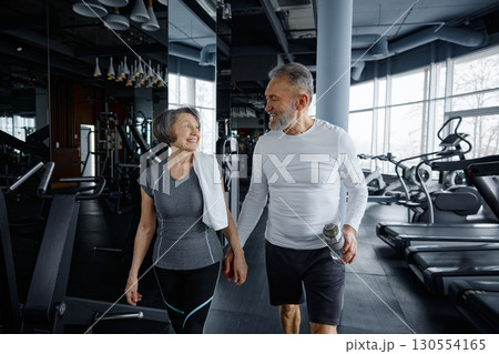 Mature man and woman are having a conversation while resting in a gym 130554165