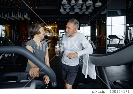 Elderly man and woman are having a conversation while resting in a gym Elderly man and woman are having a conversation while resting in a gym 130554171