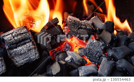 Closeup shot of a pile of charcoal with fire for a barbecue on a dark background 130554463
