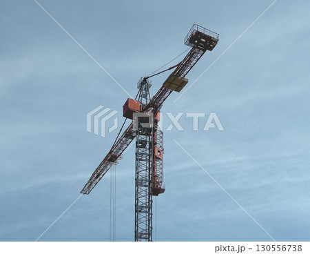 steel construction crane set against a clear blue sky. The crane is elevated and ready for lifting 130556738