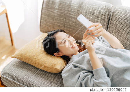 ソファに寝転がってスマホを使う女性 ソファに寝転がってスマホを使う女性 130556945