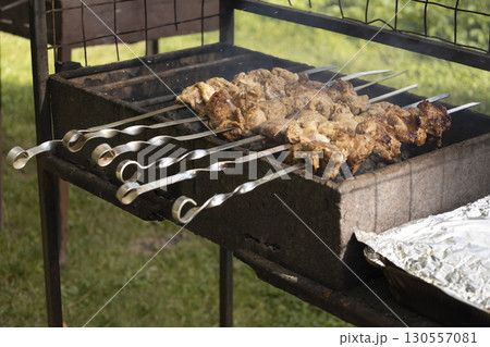 Juicy slices of meat prepare on the fire. Tasty shish kebab on skewers. Grilled marinated barbecue meat - shashlik on pork Juicy slices of meat prepare on the fire. Tasty shish kebab on skewers. Grilled marinated barbecue meat - shashlik on pork 130557081