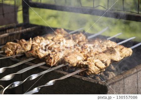Juicy slices of meat prepare on the fire. Tasty shish kebab on skewers. Grilled marinated barbecue meat - shashlik on pork Juicy slices of meat prepare on the fire. Tasty shish kebab on skewers. Grilled marinated barbecue meat - shashlik on pork 130557086