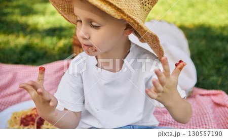 Boy with spaghetti sauce on face and fingers at picnic 130557190