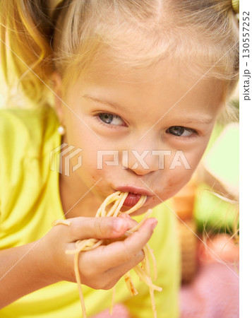 Close up of girl eating spaghetti with messy face at picnic 130557252