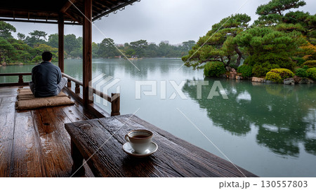 Meditating by a rainy lake with a cup of tea in a tranquil Japanese garden 130557803