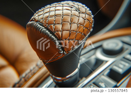 Close up of a luxurious car gear shift knob. Brown textured leather with black accents and elegant silver stitching on console. 130557845