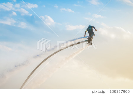 Flyboarding adventure in clear skies over the ocean during sunset with a rider soaring high. Flyboarding athlete with jet stream flying on a flyboard against the sky extreme sports Flyboarding adventure in clear skies over the ocean during sunset with a rider soaring high. Flyboarding athlete with jet stream flying on a flyboard against the sky extreme sports 130557900