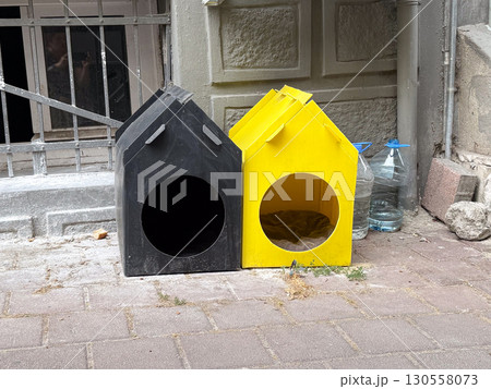 Black and yellow cat shelters placed on the street. Urban compassion, care, and coexistence with stray animals. 130558073