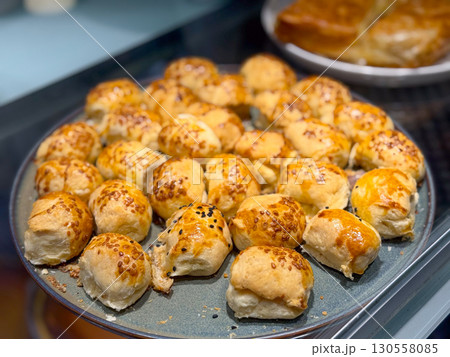 Plate of small baked rolls with golden crust and sesame seeds. Everyday nutrition, culinary tradition, and cultural lifestyle in simple handmade bread. Plate of small baked rolls with golden crust and sesame seeds. Everyday nutrition, culinary tradition, and cultural lifestyle in simple handmade bread. 130558085