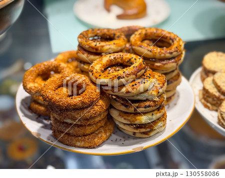 Stacks of traditional sesame bread rings on a plate in a bakery display. Culinary tradition, nourishment, and lifestyle reflected in everyday food culture. 130558086
