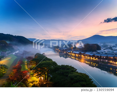 夕暮れに灯りが灯る川沿いの日本の町並みと幻想的な風景｜夕景、川、町並み、日本、夕暮れ、風景、山、和風 130559094