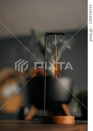 incense stick smokes on a wooden stand on a dark background. Aromatherapy, Smoke while burning incense. smoke for prayers and meditation. prayer to buddha. incense for relaxation and yoga 130559153