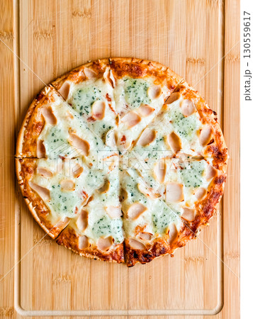 Sliced pizza with visible pieces and toppings on wooden board. Sharing, leisure and culinary enjoyment in everyday dining. Sliced pizza with visible pieces and toppings on wooden board. Sharing, leisure and culinary enjoyment in everyday dining. 130559617