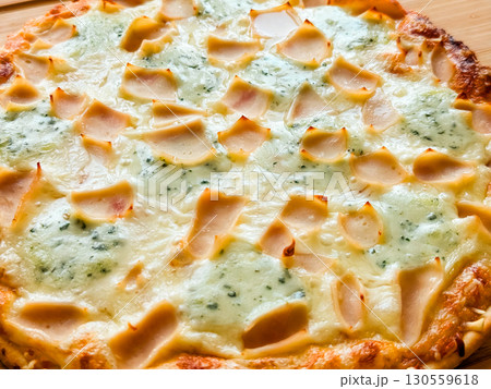 Whole baked pizza with cheese and toppings on wooden board close-up. Food, leisure and culinary lifestyle in homemade dining culture. 130559618