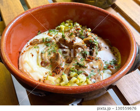 Traditional meat with mashed potatoes served in a clay bowl. Comfort, taste, and cultural richness of homemade cuisine. Traditional meat with mashed potatoes served in a clay bowl. Comfort, taste, and cultural richness of homemade cuisine. 130559676