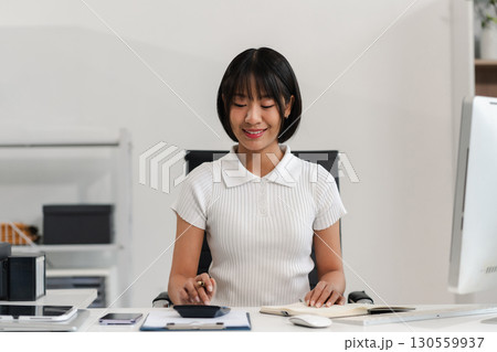 Female businessman hand using calculator and writing make note with calculate about cost at home office. Female businessman hand using calculator and writing make note with calculate about cost at home office. 130559937