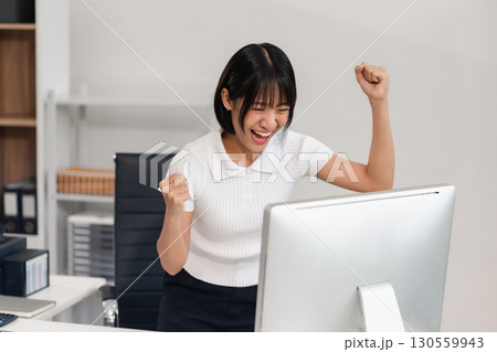 Successful business woman, excited young woman Keeping up arms and showing positive emotions, happy working in modern office on computer. Successful business woman, excited young woman Keeping up arms and showing positive emotions, happy working in modern office on computer. 130559943