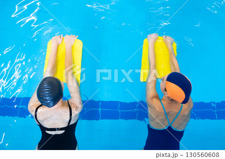 Two women swimming with kickboards in the swimming pool Two women swimming with kickboards in the swimming pool 130560608