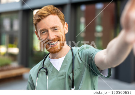 Man doctor smiling to camera while taking selfie 130560655