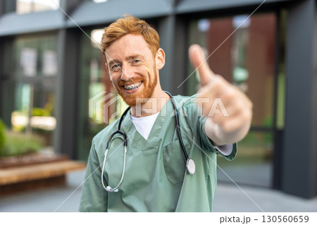 Bearded doctor man standing outdoors with thumb up gesture Bearded doctor man standing outdoors with thumb up gesture 130560659