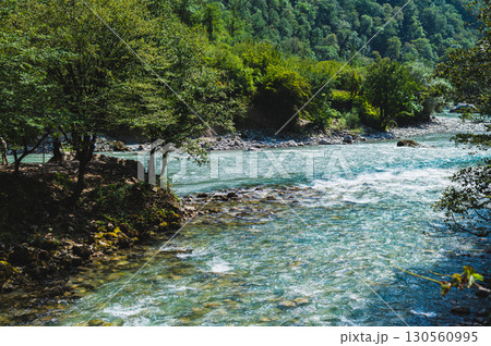 Free blue mountain rock river among forested mountains on sunny day 130560995