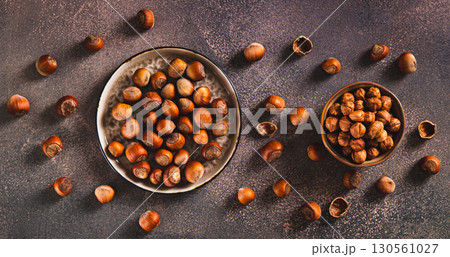 Nutritious unpeeled hazelnuts on a plate and peeled ones in a bowl top view web banner 130561027