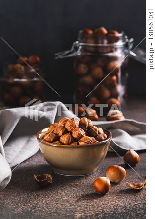 High-calorie peeled hazelnuts in a bowl on the table vertical view 130561031