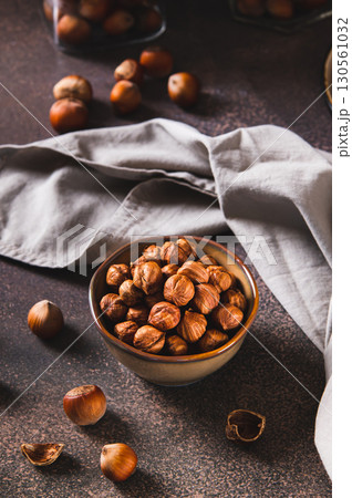Nourishing hazelnuts without shells in a bowl for diet on the table vertical view Nourishing hazelnuts without shells in a bowl for diet on the table vertical view 130561032