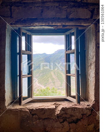 Old wooden window in stone building opens to reveal lush green mountains under cloudy sky Old wooden window in stone building opens to reveal lush green mountains under cloudy sky 130561064
