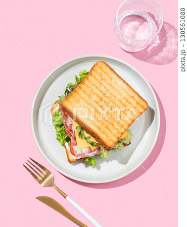 Club sandwich of toast bread with bacon, cheese, tomatoes, lettuce, arugula and sauce in a plate 130561080