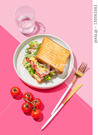 Club sandwich of toast bread with bacon, cheese, tomatoes, lettuce, arugula and sauce in a plate 130561081