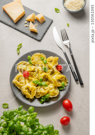 Tortellini pasta with parmesan, pesto and basil in a plate on a light background with cheese, herb Tortellini pasta with parmesan, pesto and basil in a plate on a light background with cheese, herb 130561095