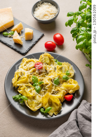 Tortellini pasta with parmesan, pesto and basil in a plate on a light background with cheese, tomato 130561099