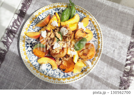 Fruit salad with cheese and honey on porcelain plate with blue pattern. Baked fruits. Food and vitamins, healthy eating. Seasonal products. 130562700