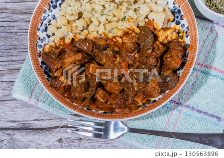 Delicious hungarian goulash with spaetzle on rustic wooden table Delicious hungarian goulash with spaetzle on rustic wooden table 130563896