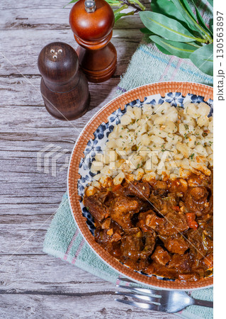 Hungarian goulash with spaetzle on rustic wooden table 130563897