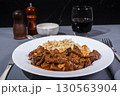 Delicious hungarian goulash with spaetzle and red wine being served on white plate 130563904