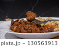 Fork lifting piece of beef from plate of goulash and spaetzle 130563913