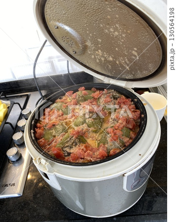 Electric rice cooker with cooked stuffed peppers and beef on kitchen counter 130564198