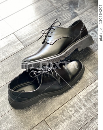 Black leather dress shoes on wooden floor with textured background 130564205