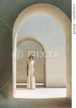A woman stands in a large, arched doorway 130564341