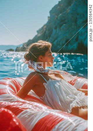 A woman is sitting in a red and white inflatable raft on a body of water 130564342