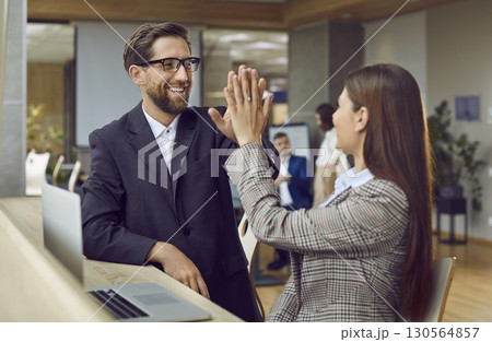 Two happy business people celebrate successful deal and give each other high five 130564857