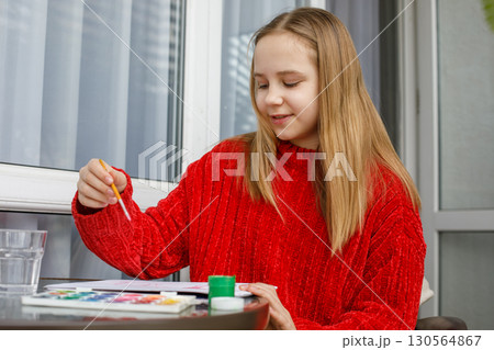 Smiling child painting with bright colors. Young girl at home, hobby and leisure Smiling child painting with bright colors. Young girl at home, hobby and leisure 130564867