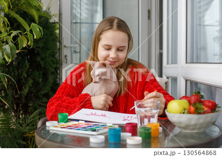 Young child girl painting and sitting with cat pet on the terrace. Kid 11 years old 130564868