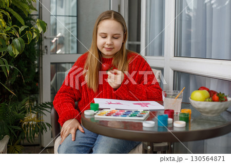 Happy young girl eating red strawberry and sitting on a balcony. Preteen child, leisure activity 130564871