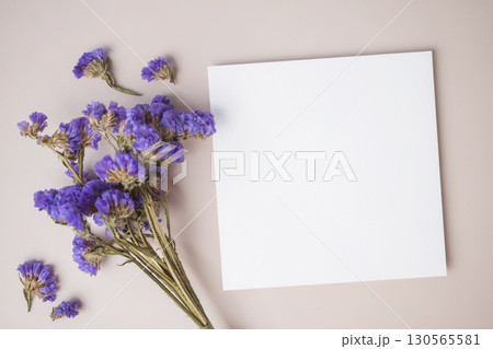 White blank greeting or invitation card with purple flower decoration on beige background. White blank greeting or invitation card with purple flower decoration on beige background. 130565581